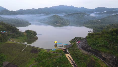 Aerial-view-of-dam-water-gate-on-Sermo-Dam-with-beautiful-view-of-misty-forest-and-hill-in-the-morning