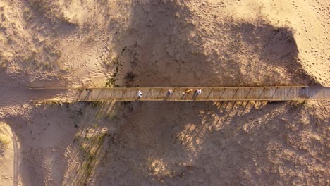 People-with-dog-cross-a-wooden-bridge-at-the-entrance-to-Punta-del-Este-City-beach-in-Uruguay-at-sunset