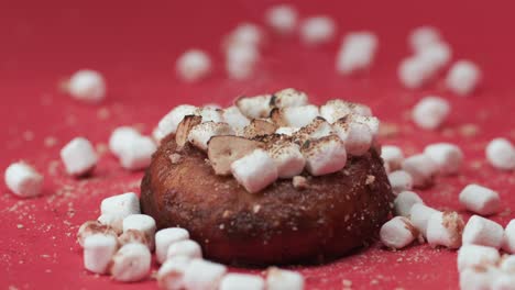 Close-up-roasting-marshmallows-on-a-chocolate-donut-in-studio,-red-background