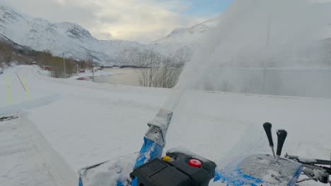 Removing-hard-and-compact-snow-near-the-road-during-winter-season-with-a-snow-blower,-static-shot