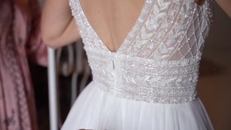 Bride-getting-ready-for-the-wedding,-Bridesmaids-helping-zipping-beautiful-white-dress,-Close-up