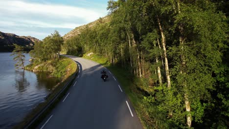 Ein-Motorradfahrer-Fährt-An-Einem-See-In-Den-Bergen-Entlang