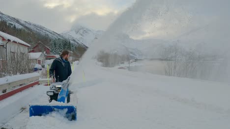 Static-shot-of-a-male-clearing-snow-with-a-big-snow-blower-during-winter-in-Northern-Europe
