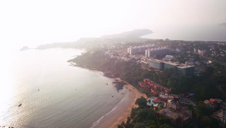 Above-the-India-tropic-holiday-beach-resorts-Goa-on-the-bay-of-the-Arabian-Sea-Indian-Ocean-sunset-with-pool-aerial-pan-circle-to-the-right