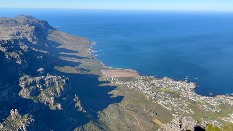 Top-of-the-world-Table-Mountain-Cape-Town-South-Africa-cliffs-stunning-epic-morning-view-downtown-city-Lions-Head-hike-fitness-exercise-lush-spring-summer-grass-flowers-green-deep-blue-ocean-pan-up