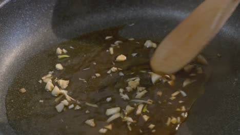 Close-up-of-fresh-garlic-being-stirred-in-a-cooking-pan