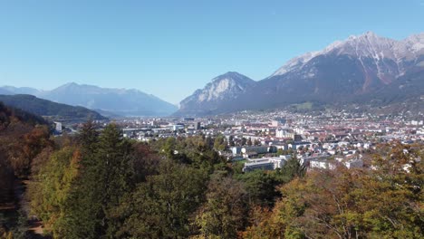 aerial-view-of-Ambras-castle-showing-the-alps-on-a-sunny-autumn-day,-with-calm-forests,-green-hills,-Innsbruck-city,-Tyrol,-Austria,-Europe