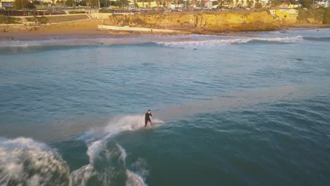 aerial-view-following-the-man-surfing-tropical-ocean-waves-on-surfboard-in-estoril,-Cascais