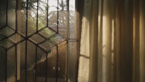 Cinematic-shot-of-early-morning-sun-rays-shining-and-peaking-through-the-curtains-of-this-window