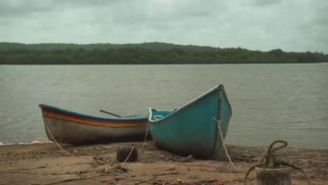 Mit-Einem-Seil-Festgebundene-Hölzerne-Fischerboote-Liegen-Im-Sand-Am-Strand-Vor-Der-Kulisse-Von-Palmen-Im-Wald-In-Goa,-Indien