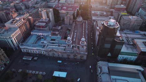 Sunrise-aerial-view-circling-above-Santiago,-Metropolitan-Cathedral-catholic-church-cityscape