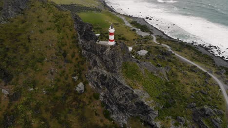 Cape-Palliser-Leuchtturm-Auf-Einer-Klippe-Mit-Meereswellen-An-Der-Felsigen-Küste-In-Neuseeland