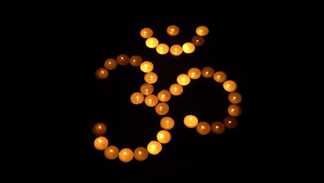 Om-symbol-from-burning-candles-on-black-background,-for-meditation-and-mantra