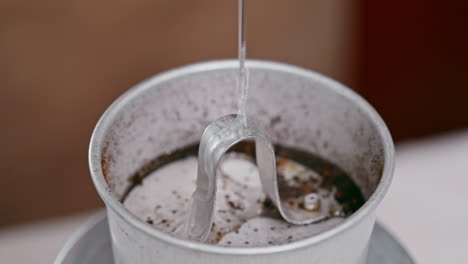 A-close-up-view-of-slowly-poured-boiling-water-into-a-Vietnamese-coffee-phin