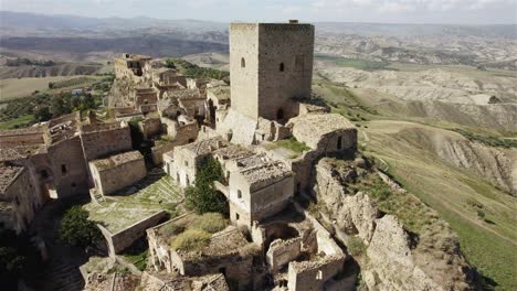 Drone-flying-in-large-circulair-motion-closeby-the-old-ruins-of-Craco-on-a-hill-in-the-south-of-Italy-in-4k