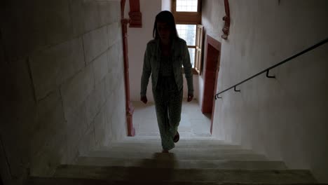 Woman-walking-up-the-stairs-in-a-dark-hallway