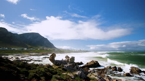 Panoramic-view-over-windy-rugged-coastline-of-Hermanus-next-to-imposing-mountain