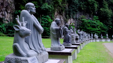 Varias-Estatuas-De-Buda-Se-Alinean-En-El-Parque-Con-La-Montaña-Al-Fondo