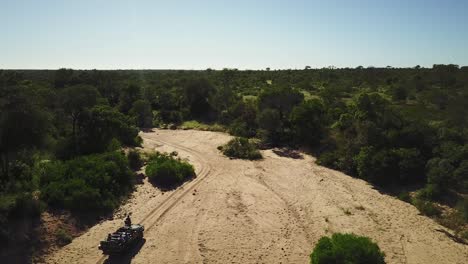 Eine-Drohnenaufnahme-Eines-Safarifahrzeugs,-Das-Durch-Ein-Ausgetrocknetes-Flussbett-In-Afrika-Fährt
