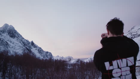 Traveller-alone-contemplates-mountain-scenery-and-takes-photos,-Lofoten,-Norway