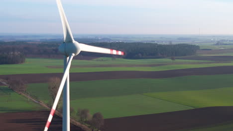 Aerial:-Rotating-Windmill-installed-on-green-farm-field-in-nature-during-sunlight-and-wind