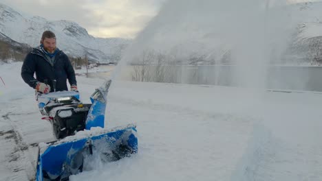 Man-removing-snow-on-a-very-cold-winter-day-in-Northern-Europe-with-a-snow-blower,-static-shot