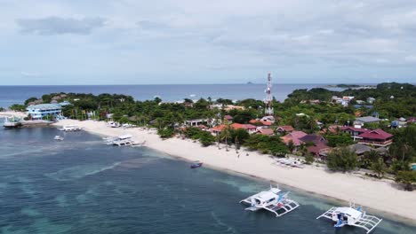 Aerial,-large-outrigger-diving-boats-moored-at-Bounty-beachfront-dive-resorts,-Malapascua-Island---Philippines