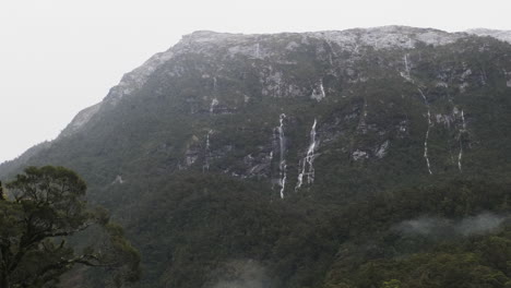 Eine-Prächtige-Felswand-Mit-Mehreren-Wasserfällen,-Die-Während-Eines-Regensturms-Herabstürzen,-Umgeben-Von-üppigem-Grün-Und-Nebel