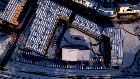 Top-down-aerial-of-residential-community-Ubuntuplein-complex-after-a-snowstorm-seen-from-above-with-roof-full-of-solar-panels-covered-in-white-snow-in-urban-development-real-estate-investment-project