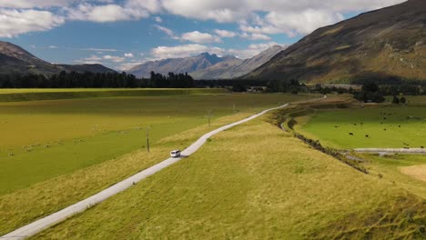 Van-Driving-Through-Scenic-Mountains-And-Green-Pasture-Landscape-Of-Earnslaw-Burn-Track-In-Otago,-New-Zealand---aerial-shot
