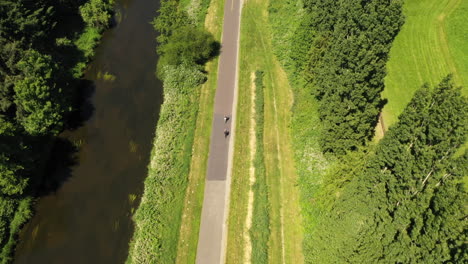 Aerial-view-of-bicyclist-on-a-long-road-hidden-by-trees