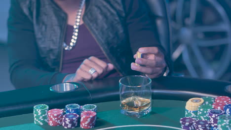 Pokerspieler-Hält-Casino-Chips-Und-Ein-Glas-Whiskey-Auf-Dem-Tisch