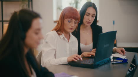 Businesswomen-working-on-laptop-at-desk-in-office.