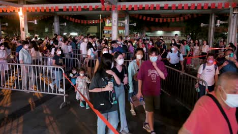 Visitors-walk-through-a-long-queue-to-enter-a-nighttime-lantern-show,-which-symbolizes-prosperity-and-good-fortune,-at-the-Wong-Tai-Sin-temple-during-the-Mid-Autumn-Festival-