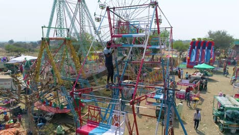 Drone-circles-around-an-Indian-worker-on-a-manual-driven-Ferris-wheel