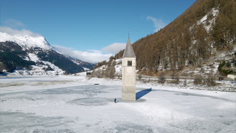 Aerial-View-Of-Submerged-Bell-Tower-At-Frozen-Lake-Reschen
