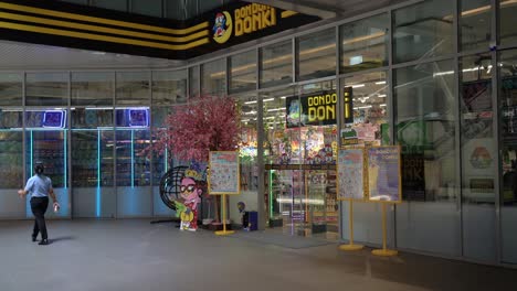 Lady-walked-past-the-new-24-hour-Don-Don-Donki,-a-famous-Japanese-multinational-discount-store-chain-supermarket-at-Thaniya-Silom,-Bangkok,-Thailand