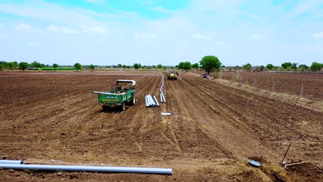 Aerial-camera-zooming-in,-ground-shot-of-excavation-working-and-digging-for-water-pipeline-at-agricultural-farm