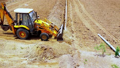 heavy-duty-excavation-machine-Cover-up-with-soil-into-underground-water-pipeline-at-Indian-agricultural-land