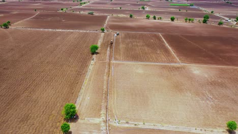 Aerial-Cinematic-shot-of-excavation-digging-in-the-farm-land-for-the-water-pipeline,-hot-summer-seasons