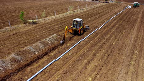 Aerial-rotted-shot-of-excavation-digging-deep-agricultural-soil-for-water-pipeline