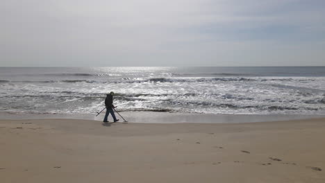 Man-With-Metal-Detector-Getting-Feet-Wet-By-Waves