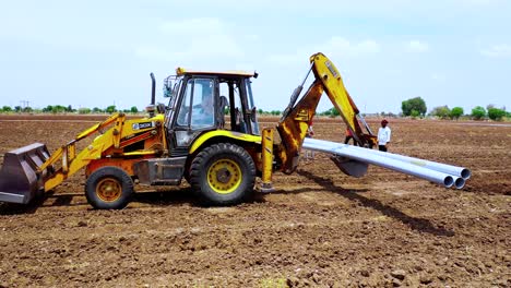 Excavation-machine-moving-reverse-with-holding-pipeline-for-the-fittings-in-the-farm