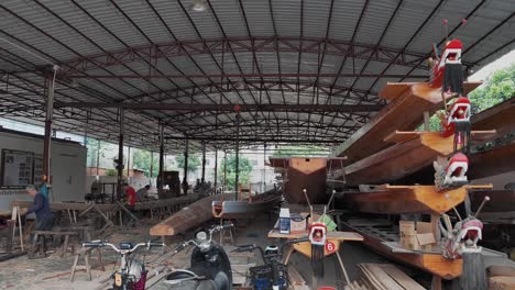 Kleine-Traditionelle-Werkstatt-Mit-Seitlich-Aufgestapelten-Handgefertigten-Drachenbooten-Aus-Holz