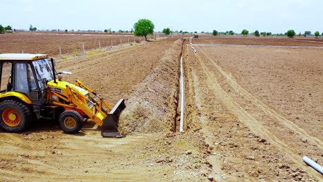 Follow-shot-of-earthmoving-machine-cover-up-Underground-water-pipeline-with-soil-In-India