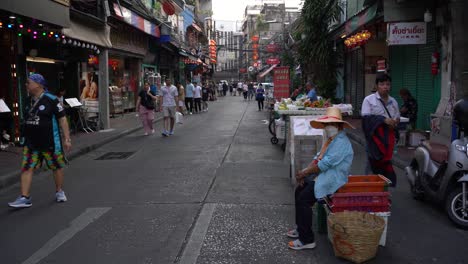 Point-of-view-of-people-walking-on-the-street-heading-to-the-main-road-of-the-famous-Chinatown-in-Bangkok,-Thailand