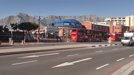 Red-Sightseeing-bus-arrives-at-main-terminal-in-front-of-aquarium-in-Cape-Town
