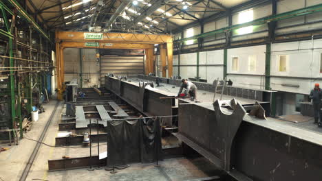 Workers-assembling-steel-bridge-in-industrial-steelwork-factory-hall