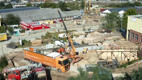 Mobile-crane-moving-steel-beams-from-truck-at-urban-construction-site