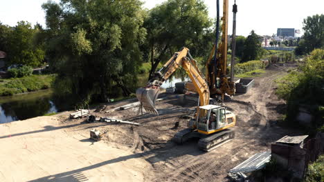 Excavator-with-raised-hydraulic-bucket-driving-at-river-dredging-site